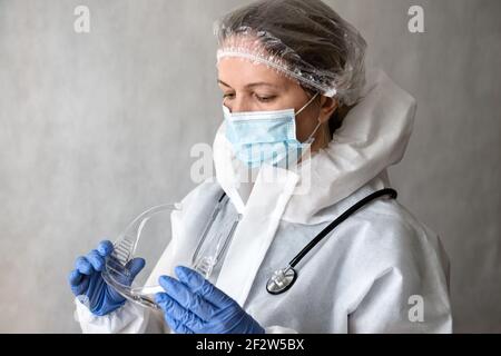 Doctor in personal protective equipment (PPE) from COVID-19, portrait of tired woman physician in medical coverall due to coronavirus, female doctor w Stock Photo