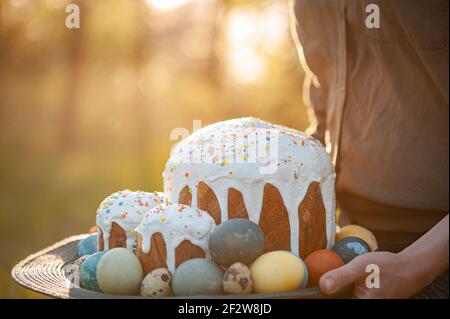 Girl holding a wooden plate with easter cake and eggs Stock Photo