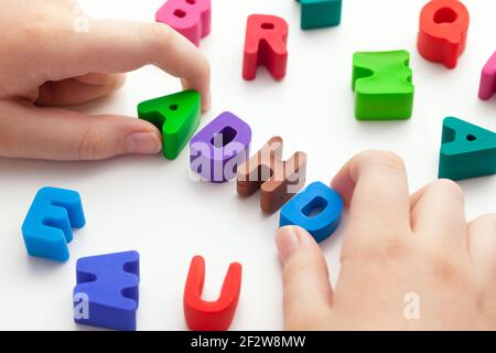 A young boy holding the abbreviation ADHD that is made out of polymer clay letters. ADHD is Attention deficit hyperactivity disorder. Stock Photo