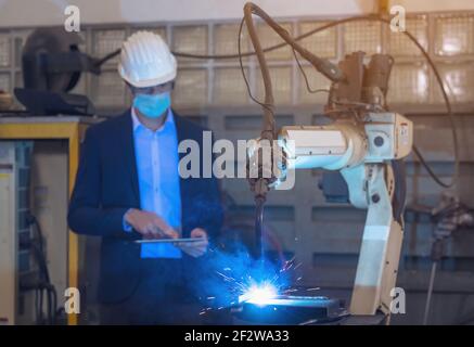 Engineer check and control automation robot arms machine in intelligent factory industrial on real time monitoring system software. Welding robotics a Stock Photo