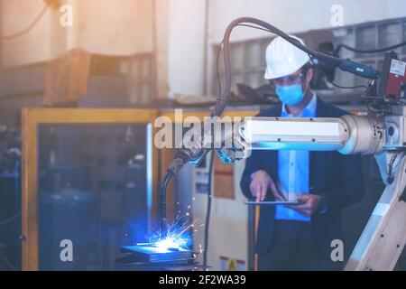 Engineer check and control automation robot arms machine in intelligent factory industrial on real time monitoring system software. Welding robotics a Stock Photo