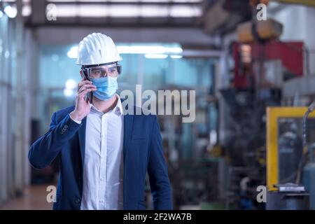 Mechanical worker with mask talking on the phone in a factory Stock Photo