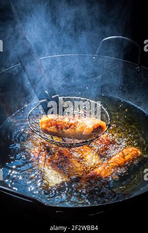 Fried tasty spring rolls in a wok on hot oil. Vietnamese cuisine. Stock Photo