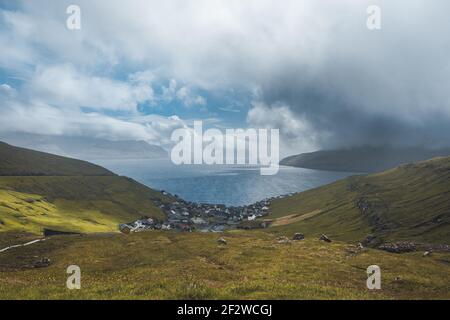 Sun shining on small village on the the northern most village on Stremoy in the Faroe Islands with blue sky and flowers. Stock Photo