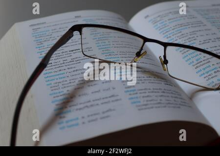 The reader is tired on his dictionary, he has kept his spectacles on the book. Stock Photo