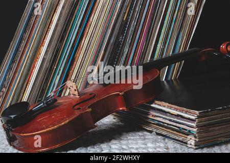 a violin in front of a pile of old vinyl records Stock Photo