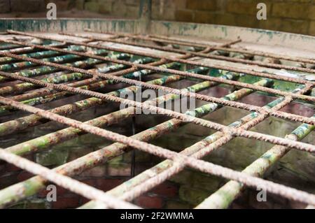 Reinforcement iron safety cover on a well. The cover is made of rusty reinforcement iron and the concrete of the well is starting to weather Stock Photo