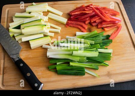 Sliced Vegetables on a Bamboo Cutting Board: Red bell pepper, zucchini, and scallions on a bamboo cutting board Stock Photo