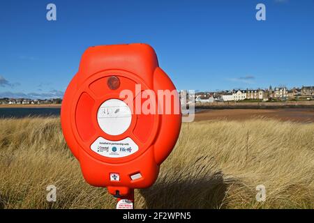 Red life saving equipment box on beach at Elie in Fife, Scotland on a sunny day with blue sky. Stock Photo