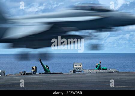 U.S. Navy deck crew signal to launch an FA-18E Super Hornet fighter aircraft assigned to the Blue Diamonds of Strike Fighter Squadron 146, off the flight deck aboard the Nimitz-class aircraft carrier USS Theodore Roosevelt March 11, 2021 in the Indian Ocean. Stock Photo