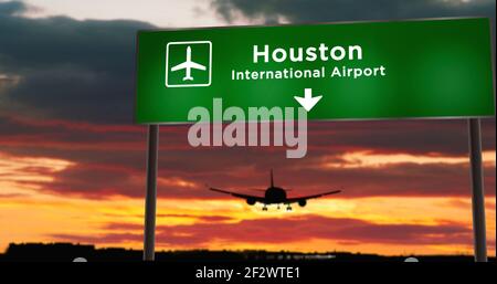 Airplane silhouette landing in Houston, Texas, USA, United States. City arrival with airport direction signboard and sunset in background. Trip and tr Stock Photo