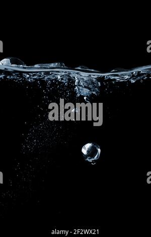 Splashing and bubbles on a clear water liquid surface. Isolated on a black Stock Photo