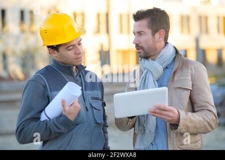 manager of a factory showing tablet to worker Stock Photo