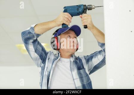 senior man repairing shelf in the kitchen housework Stock Photo