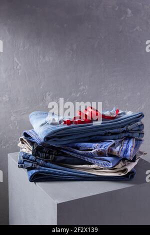 Denim jeans and belt at old grey cube near grey wall background texture.  Stack classic jeans fashion at abstract surface Stock Photo