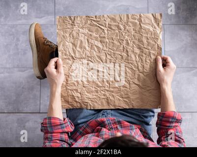 Men's hand holding wrinkled old craft paper blank. Male hand and crumpled paper, top view Stock Photo