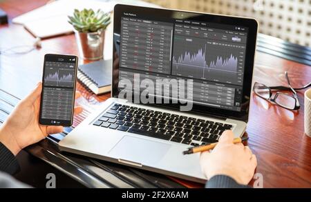Stock exchange market analysis, Man working with a laptop, monitoring app on screen, office desk background. Trade platform, forex trading. Binary opt Stock Photo