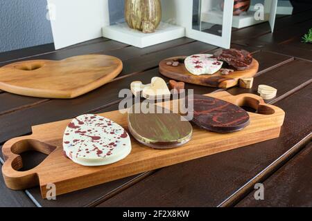 Several 2D chocolate Easter eggs (ovos de Pascoa) next to heart-shaped woods. In the background traditional Easter eggs in boxes. Stock Photo