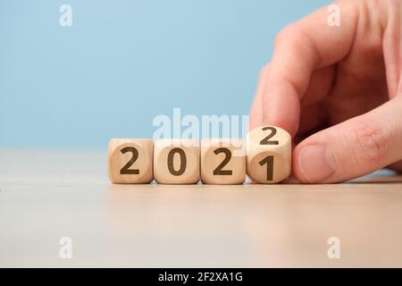 Concept of changing the year from 2021 to 2022 on wooden cubes by hand Stock Photo