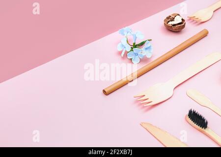 Eco friendly disposable utensils made of bamboo wood and paper on a isometric pink background. Draped spoons, fork, toothbrush, knives, bamboo tubes o Stock Photo