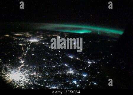 The city lights of Moscow and its suburbs seemingly branch out towards an aurora seen from the International Space Station as it orbited 263 miles above February 26, 2021 in Earth Orbit. Stock Photo