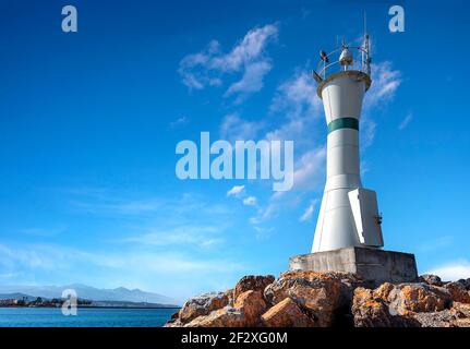 small lighthouse standing on rocks in black and white Stock Photo