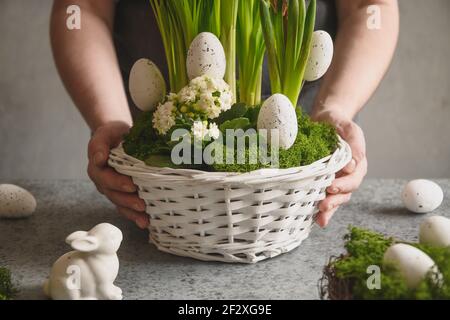 DIY Easter table centerpiece with festive eggs, moss and bunny. Spring composition. Floral workshop. Stock Photo