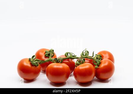 Fresh Tomatoes Isolated on White Background. Bunch of fresh, red tomatoes with green stems Stock Photo