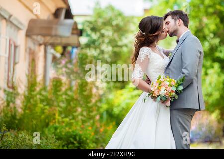 The groom and bride with bouquet stands in the park Stock Photo