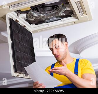 The repairman repairing ceiling air conditioning unit Stock Photo
