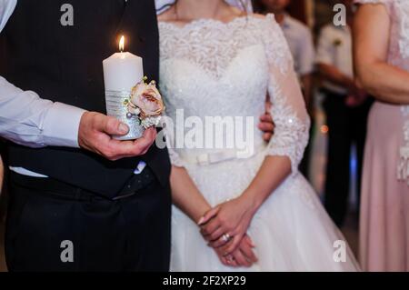 Wedding traditions family lights. Candle in the hands of the newlyweds Stock Photo