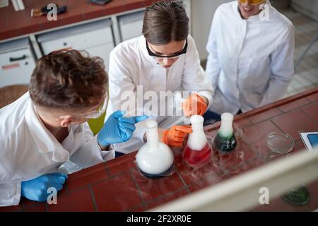 Three young laborant technicians examining chemical reactions in the lab Stock Photo