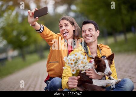 close up of young caucasian couple taking selfie with their dog in a lap, making funny faces Stock Photo