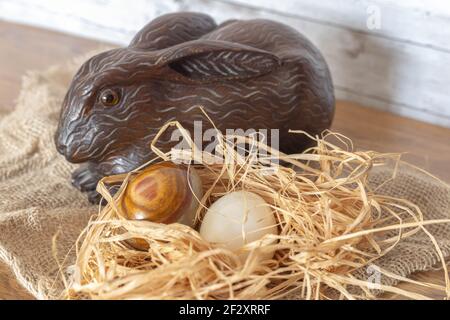 Selective focus of a wooden Easter bunny guarding holiday eggs for children's fun at religious celebration Stock Photo
