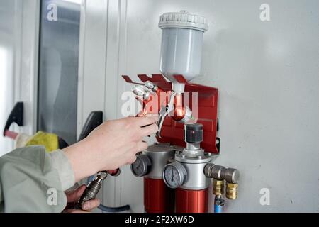 Crop unrecognizable male technician taking modern spray gun for painting car in service Stock Photo