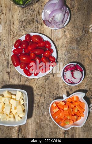 Top view composition of various fresh vegetables including radish cherry tomatoes onion on wooden table Stock Photo