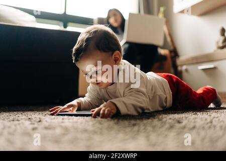 Content little baby boy lying on fluffy carpet and watching funny video on  mobile phone in light living room Stock Photo - Alamy