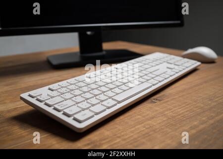 White modern keyboard and mouse near computer placed on wooden table Stock Photo