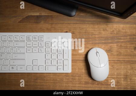 Top view of white modern keyboard and mouse near computer placed on wooden table Stock Photo