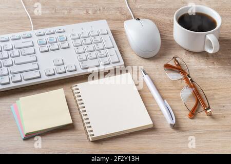PC keyboard, mouse, paper notepad, glasses and cup of coffe on a desk. Workplace at the computer at home or in the office. Online business, education. Stock Photo