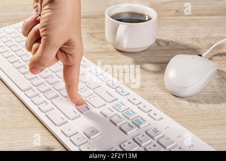 Person finger peessed down the enter key on the white PC keyboard. Concepts of confirm agreement or product order, online work, business and shopping, Stock Photo