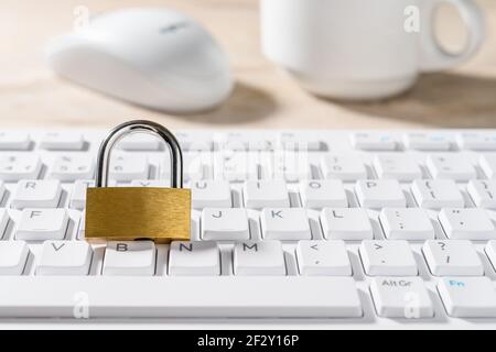Metal padlock on a white computer keyboard. Closed lock on a desktop keypad. Computer and internet security, save confidential data concepts. High key Stock Photo