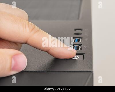 Finger is ready to press down the On Off button on the personal computer system unit. Power button on the top of desktop PC tower case. Closeup. Stock Photo