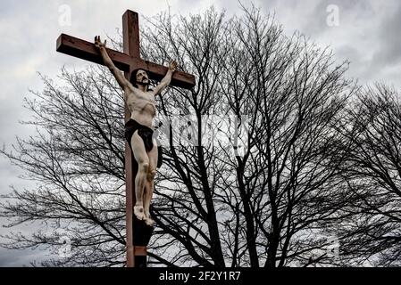 Realistic and dramatic looking statue of Jesus Christ on the crucifix in a cemetery Stock Photo