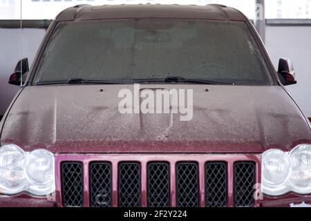 dirty red car windshield wipers covered with a layer of dust abandoned vehicles in the parking lot front view, nobody. Stock Photo