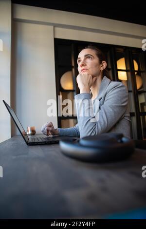 business woman with thoughtful expression while working in the office puts her hand under her chin. Stock Photo