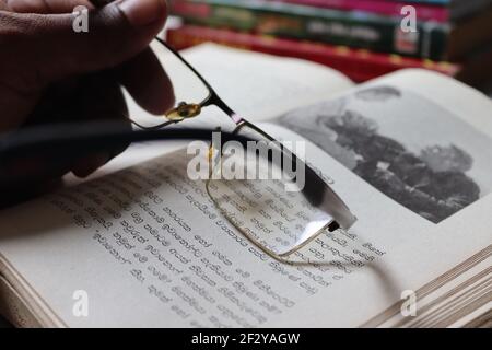 The reader is tired; he has kept his spectacles on the book. Stock Photo