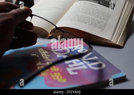 The reader is tired; he has kept his spectacles on the book. Stock Photo