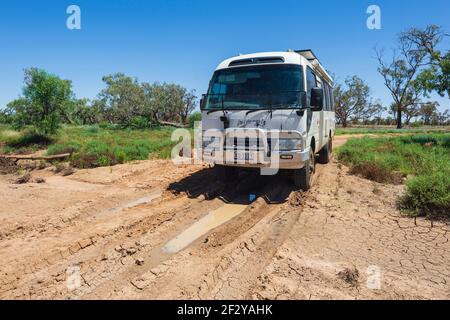 Off road Toyota Coaster motorhome motoring on a muddy Outback road