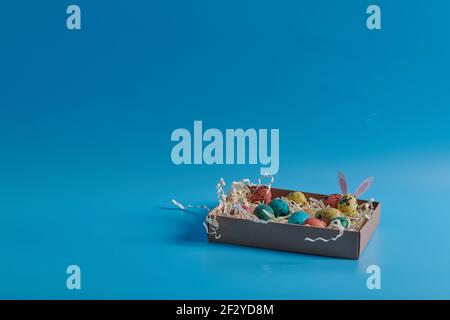 colored eggs in a box on a blue background Stock Photo